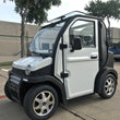 Load image into Gallery viewer, Compact white electric vehicle parked in an outdoor lot.